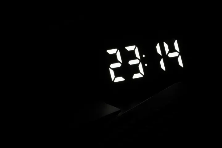 Réveil numérique affichant 23 h 14 dans une chambre sombre